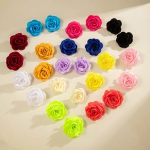Boucles d'oreilles camélia en tissu multicolore disposées en forme de cœur sur blanc