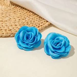 Boucles d'oreilles élégantes en tissu bleu vif avec pétales superposés sur fond neutre