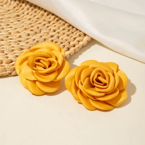 Boucles d'oreilles élégantes en tissu camélia jaune sur tapis tissé et soie douce