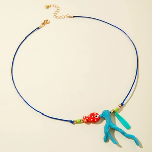 Dettaglio dei ciondoli a forma di pesce e corallo su una collana blu scuro fatta a mano