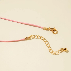 Dettaglio della collana in cordino rosa intrecciato a mano con chiusura dorata e catena