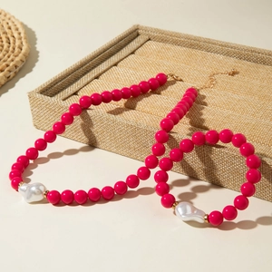 Détail d'un ensemble de bijoux en perles rouge rose avec perles baroques et or