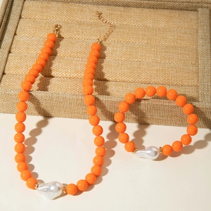 Détail d'un ensemble de bijoux en perles orange avec perles baroques et fermoir doré