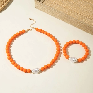 Détail d'une parure de bijoux en perles orange avec perles baroques sur plateau