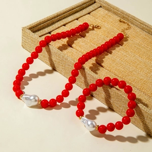 Détail d'un ensemble collier et bracelet en perles rouges avec perles baroques et fermoirs dorés