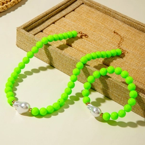 Ensemble de bijoux en perles vert néon avec perles baroques sur plateau brun
