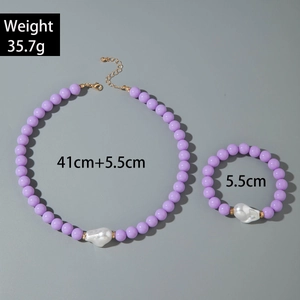 Détail de parure bijoux en perles violettes avec perle baroque et fermoir doré