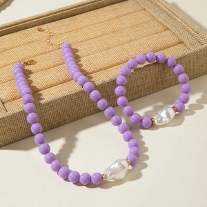 Détail d'un ensemble de bijoux en perles violettes avec grande perle baroque et fermoir doré