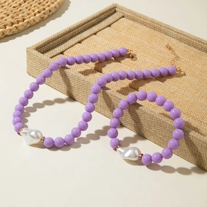 Détail du collier de perles lilas et perles baroques avec fermoirs dorés sur l'écrin