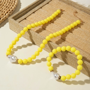 Détail de parure de bijoux en perles jaunes avec pendentifs perles baroques sur plateau