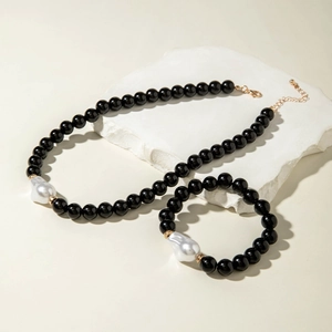 Détail de parure collier et bracelet avec perles noires brillantes et perles baroques