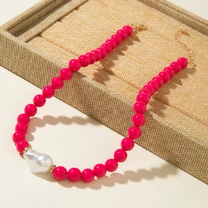 Détail d'un collier de perles roses et d'une perle baroque blanche sur un plateau décoré