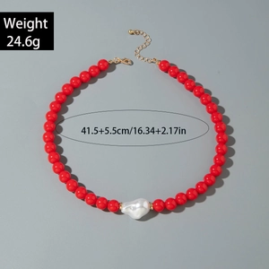 Détail d'un collier de perles rouges avec perle baroque et fermoir doré