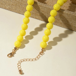Détail du collier à perles jaunes avec fermoir mousqueton doré et chaîne en métal ajustable
