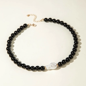 Détail d'un collier de perles noires rondes avec une perle baroque blanche au centre