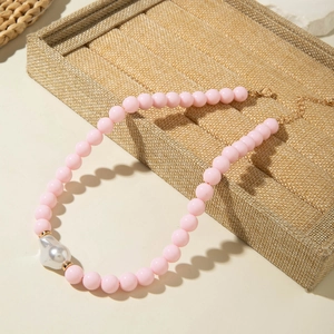 Détail du collier de perles roses avec un pendentif créatif en forme de cœur irrégulier