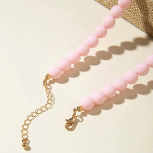 Gros plan du collier en perles roses avec fermoir mousqueton doré et chaîne d'extension