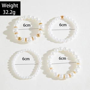 Detailed view of a 4-piece white faux pearl bracelet set with gold heart and bead accents