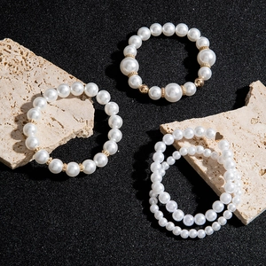 Detailed view of multilayer pearl bracelet set with gold beads on stone surface