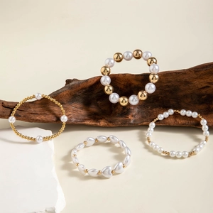 Detail of four-piece gold beaded bracelet set with faux pearls and heart charms