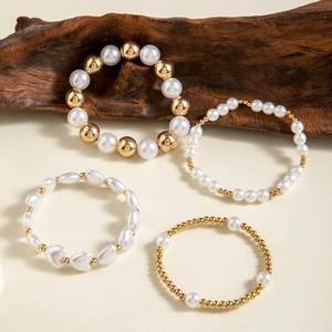 Detailed view of four pearl and gold bead bracelets with heart accents and baroque style