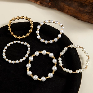 Detail of 5-piece gold beads and white faux pearls bracelet set on black velvet display tray
