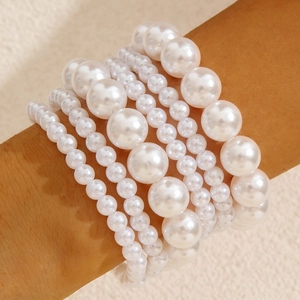 Close-up of four-piece layered pearl bracelet set with heart charms on model wrist