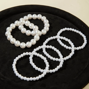 Macro shot of 4-piece white faux pearl bracelet set on black velvet jewelry tray
