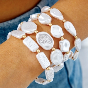 Close-up of four-piece pearl bracelet set with golden beads on a wrist