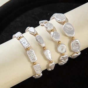 Detail of four-piece baroque pearl bracelet set with gold beads on beige jewelry display roll