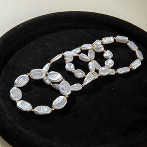 Detail of luxury pearl bracelet set with white pearls and gold metal spacers on black velvet