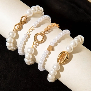 Close-up of four-piece faux pearl bracelet set with gold heart and shell charms