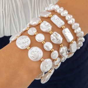 Close-up of four-piece gold and pearl bracelet set on a woman's wrist with elegant beads