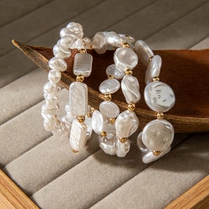 Close-up of Baroque irregular white pearl bracelets with golden beads on a wooden tray