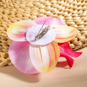 Detailed back view of phalaenopsis orchid brooch with metal pin on textured mat