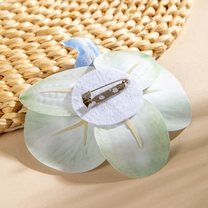Macro detail of orchid flower brooch back with silver metal pin and fabric texture
