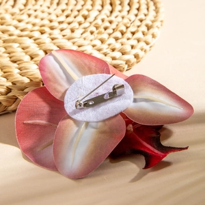 Detail of orchid brooch back featuring silver metal safety pin and white fabric base