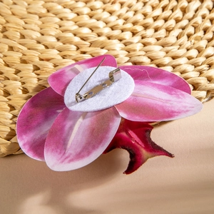Detail view showing metal safety pin on pink faux orchid flower brooch with felt backing