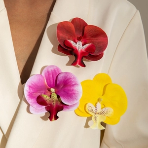 Vibrant faux moth orchid brooches in red, pink, and yellow on a white blazer lapel