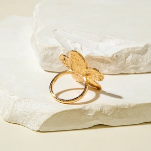 Detailed close-up of a gold-plated flower ring with intricate hammered texture on stone