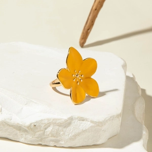 Detailed macro shot of a vintage gold lava ring with a yellow enamel flower on a white rock