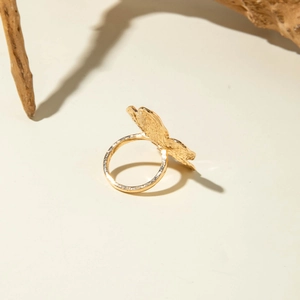 Detail of gold lava flower ring with organic texture on a minimalist wooden background