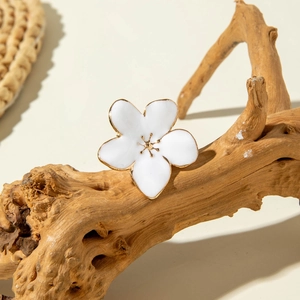 Macro detail of white enamel flower brooch with gold edges on a natural wood branch