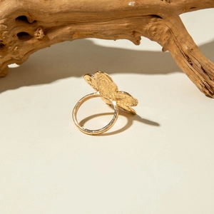 Detailed view of vintage gold floral ring with irregular lava texture on wood background