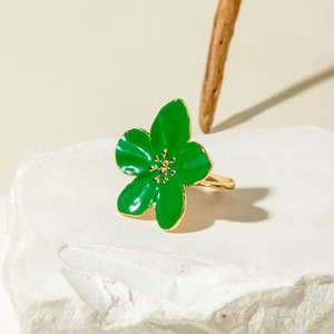 Detail of a green enamel flower ring with gold stamens on a white mineral stone base