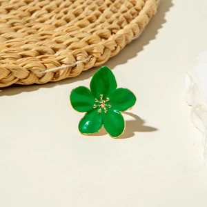 Macro shot of green enamel flower ring with golden stamens on neutral background