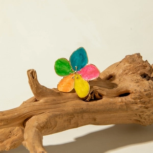 Macro detail of a colorful enamel five-petal flower ring on natural driftwood background