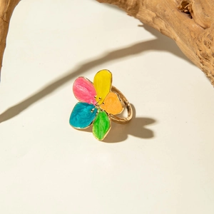 Macro view of colorful enamel flower ring with gold metal band on a natural wood surface