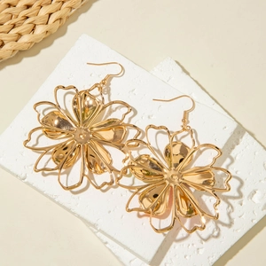Detailed view of large gold layered flower earrings on decorative stone pedestals