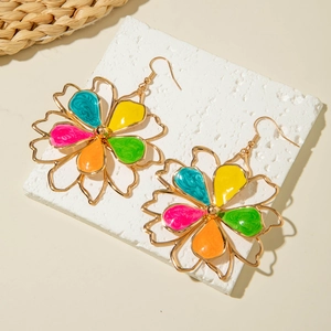 Detailed macro of large floral earrings with colorful enamel petals and gold wire framing
